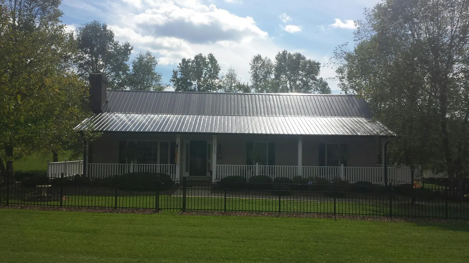 Gray metal roof on a brick ranch with a full width front porch — Gutter Guard Installation work by our crew in Big Timber