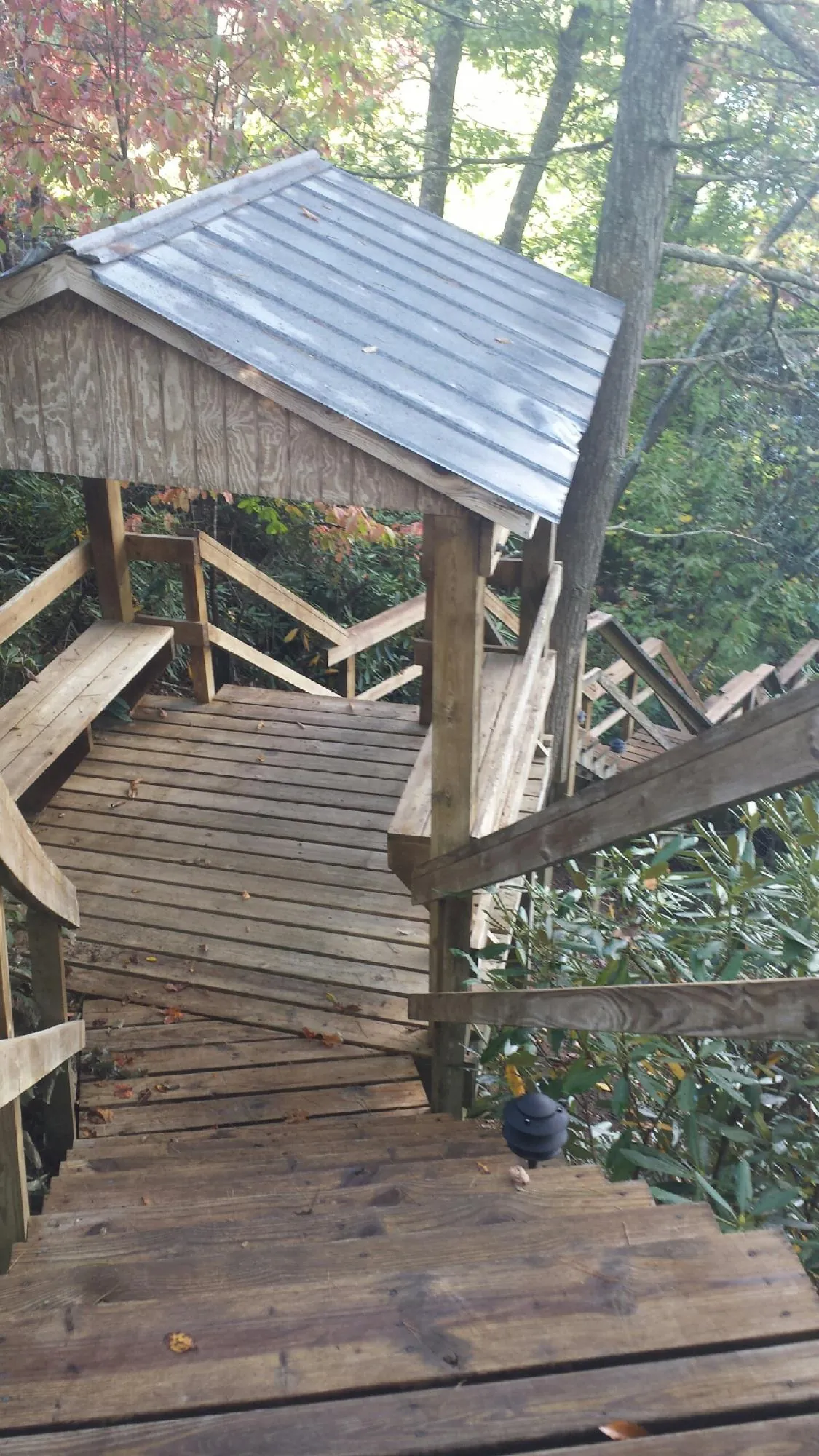 Metal roofed shelter over wooden steps on a wooded walkway — Skylight Repair & Installation work by our crew in Big Timber