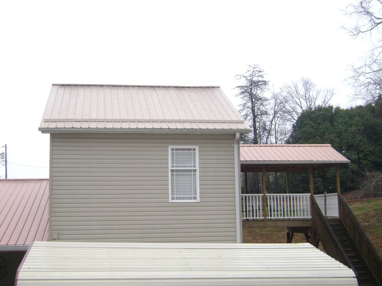 Tan metal roofs on a two story addition and attached porch, from a Roof Replacement job in Big Timber