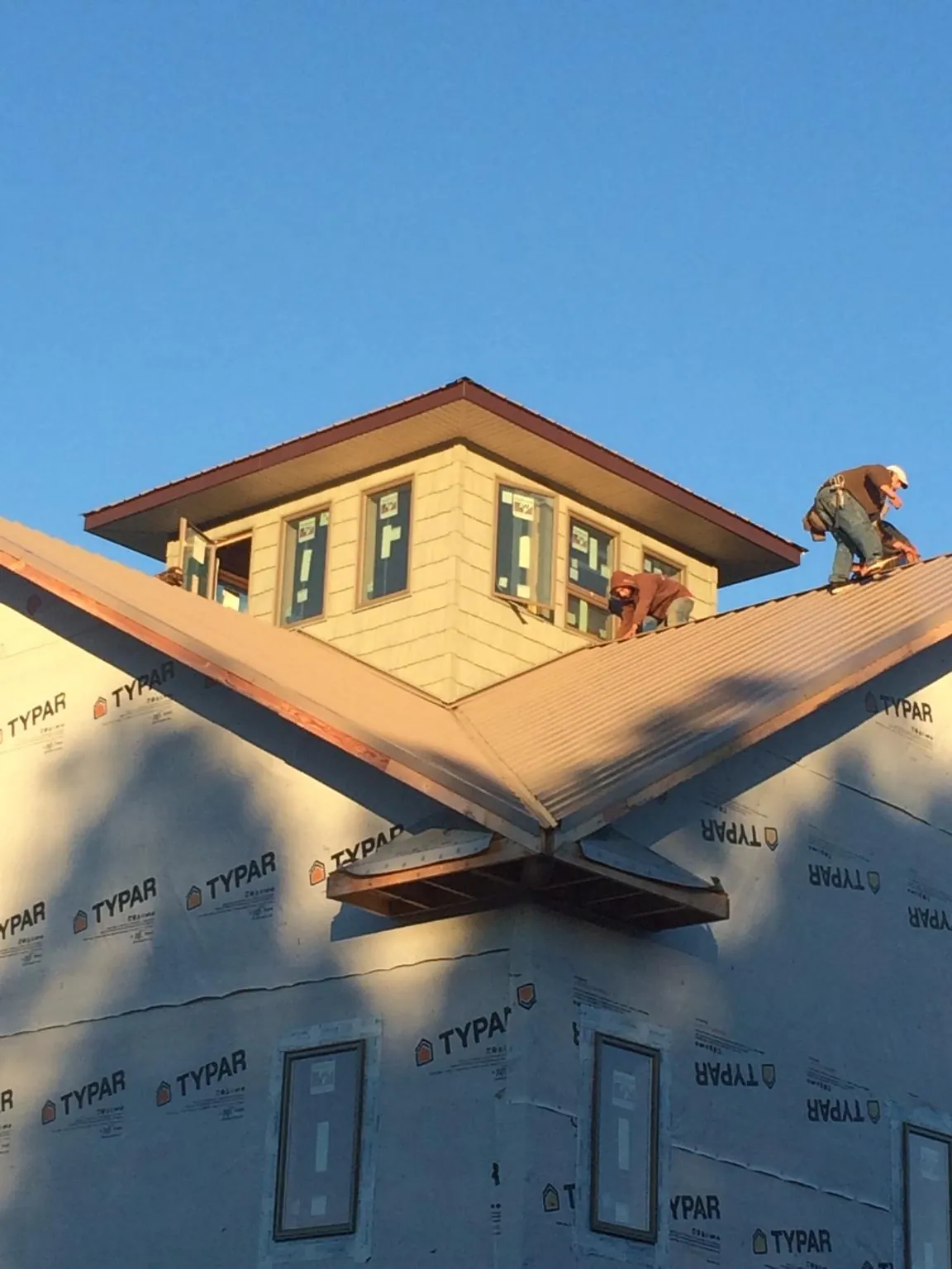 Roofers working around a rooftop cupola on a new metal roof at sunset — Roof Waterproofing in Big Timber by Roofing Brothers